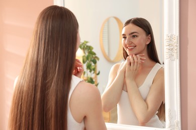 Photo of Beautiful woman looking at herself in mirror indoors