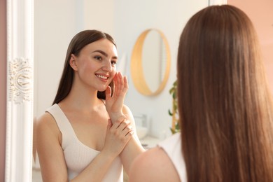 Photo of Beautiful woman looking at herself in mirror indoors