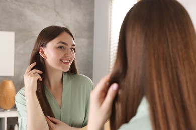 Photo of Beautiful woman looking at herself in mirror indoors