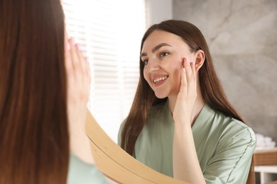 Photo of Beautiful woman looking at herself in mirror indoors