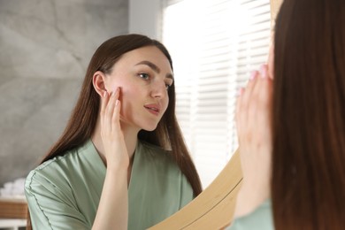 Photo of Beautiful woman looking at herself in mirror indoors