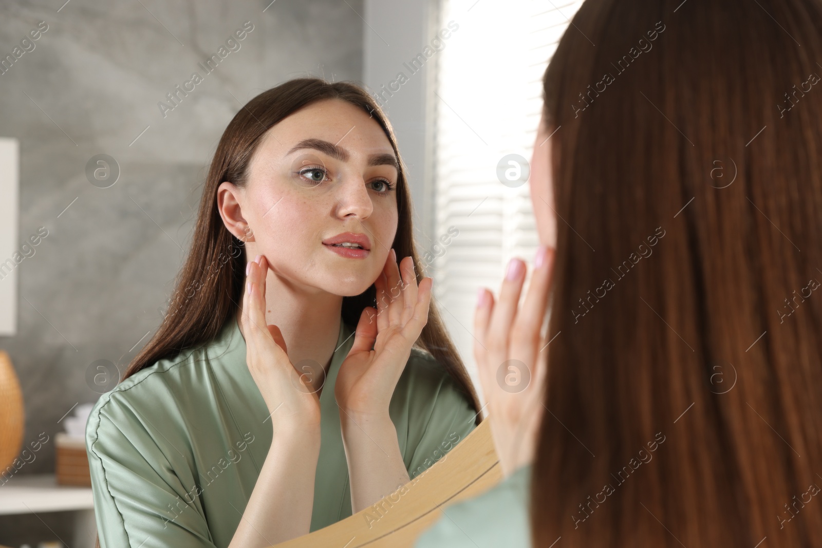 Beautiful woman looking at herself in mirror indoors Photo of Beautiful woman looking at herself in mirror indoors