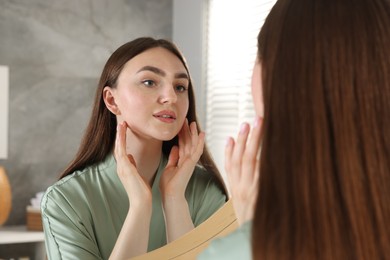 Photo of Beautiful woman looking at herself in mirror indoors