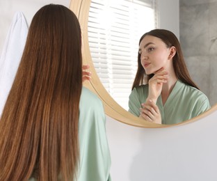 Photo of Beautiful woman looking at herself in mirror indoors
