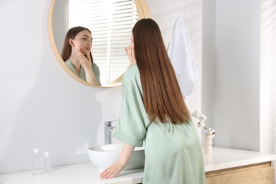 Photo of Beautiful woman looking at herself in mirror indoors
