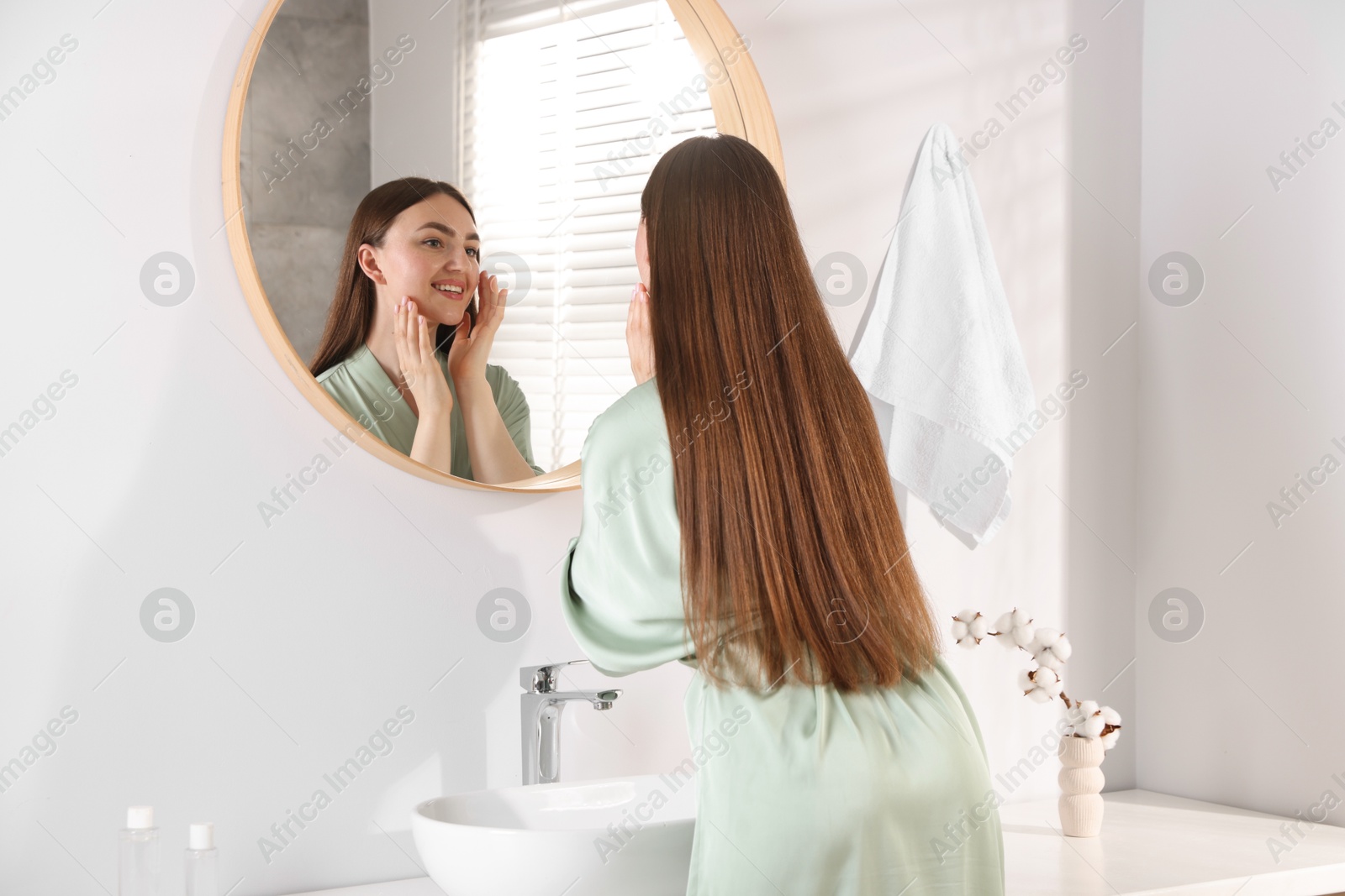 Beautiful woman looking at herself in mirror indoors Photo of Beautiful woman looking at herself in mirror indoors