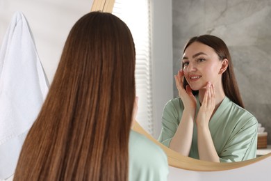 Photo of Beautiful woman looking at herself in mirror indoors