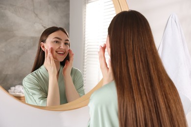 Photo of Beautiful woman looking at herself in mirror indoors