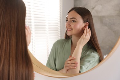 Photo of Beautiful woman looking at herself in mirror indoors