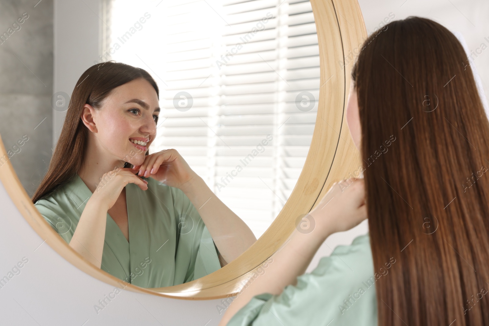 Beautiful woman looking at herself in mirror indoors Photo of Beautiful woman looking at herself in mirror indoors