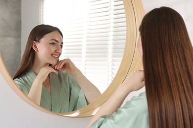Photo of Beautiful woman looking at herself in mirror indoors