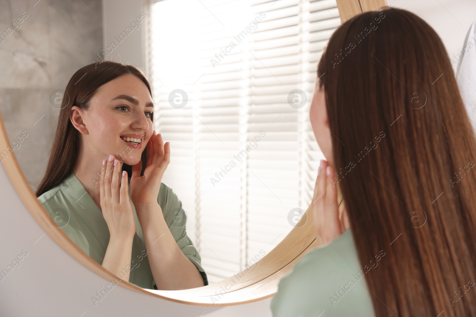 Beautiful woman looking at herself in mirror indoors Photo of Beautiful woman looking at herself in mirror indoors