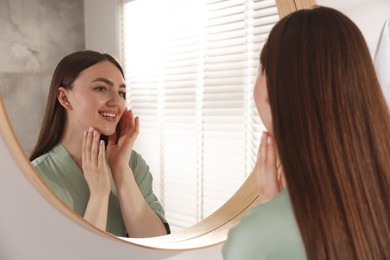 Photo of Beautiful woman looking at herself in mirror indoors