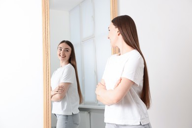 Photo of Beautiful woman looking at herself in mirror indoors