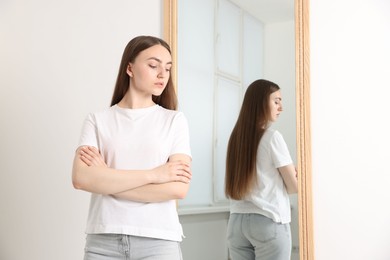 Photo of Beautiful young woman posing near mirror indoors