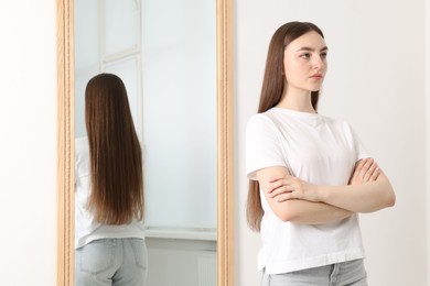 Photo of Beautiful young woman posing near mirror indoors