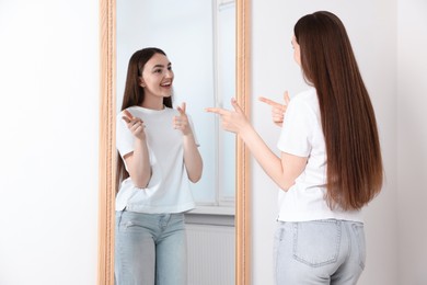 Photo of Beautiful woman looking at herself in mirror indoors