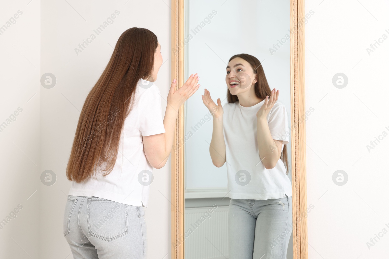 Beautiful woman looking at herself in mirror indoors Photo of Beautiful woman looking at herself in mirror indoors
