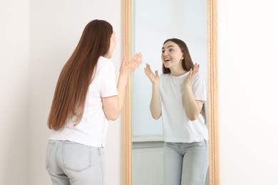 Photo of Beautiful woman looking at herself in mirror indoors