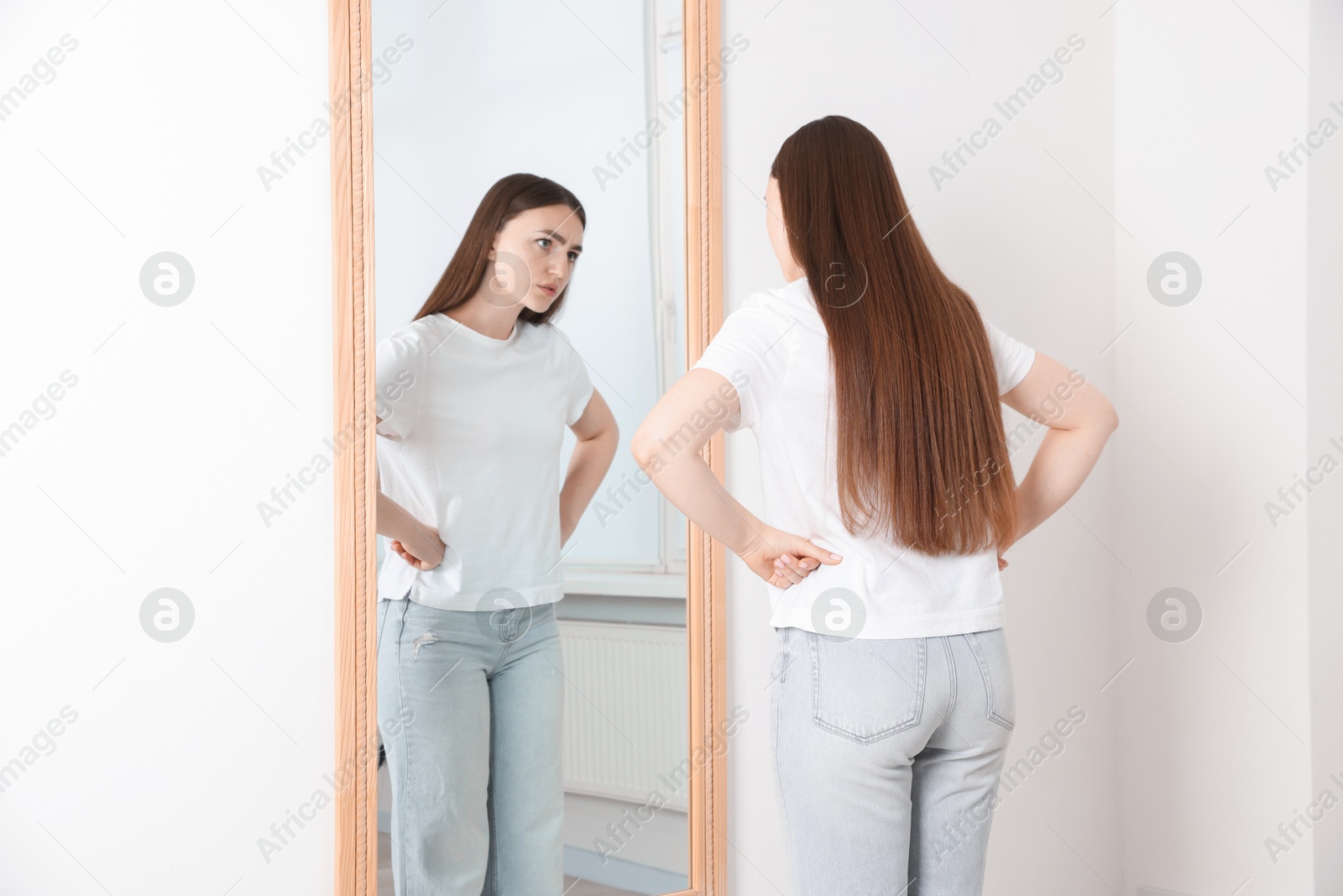 Beautiful woman looking at herself in mirror indoors Photo of Beautiful woman looking at herself in mirror indoors