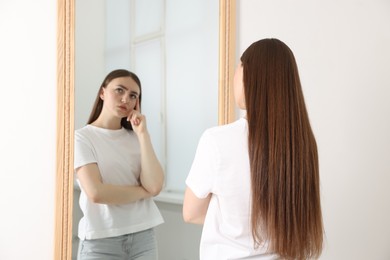 Photo of Beautiful young woman posing near mirror indoors