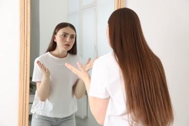 Photo of Beautiful woman looking at herself in mirror indoors