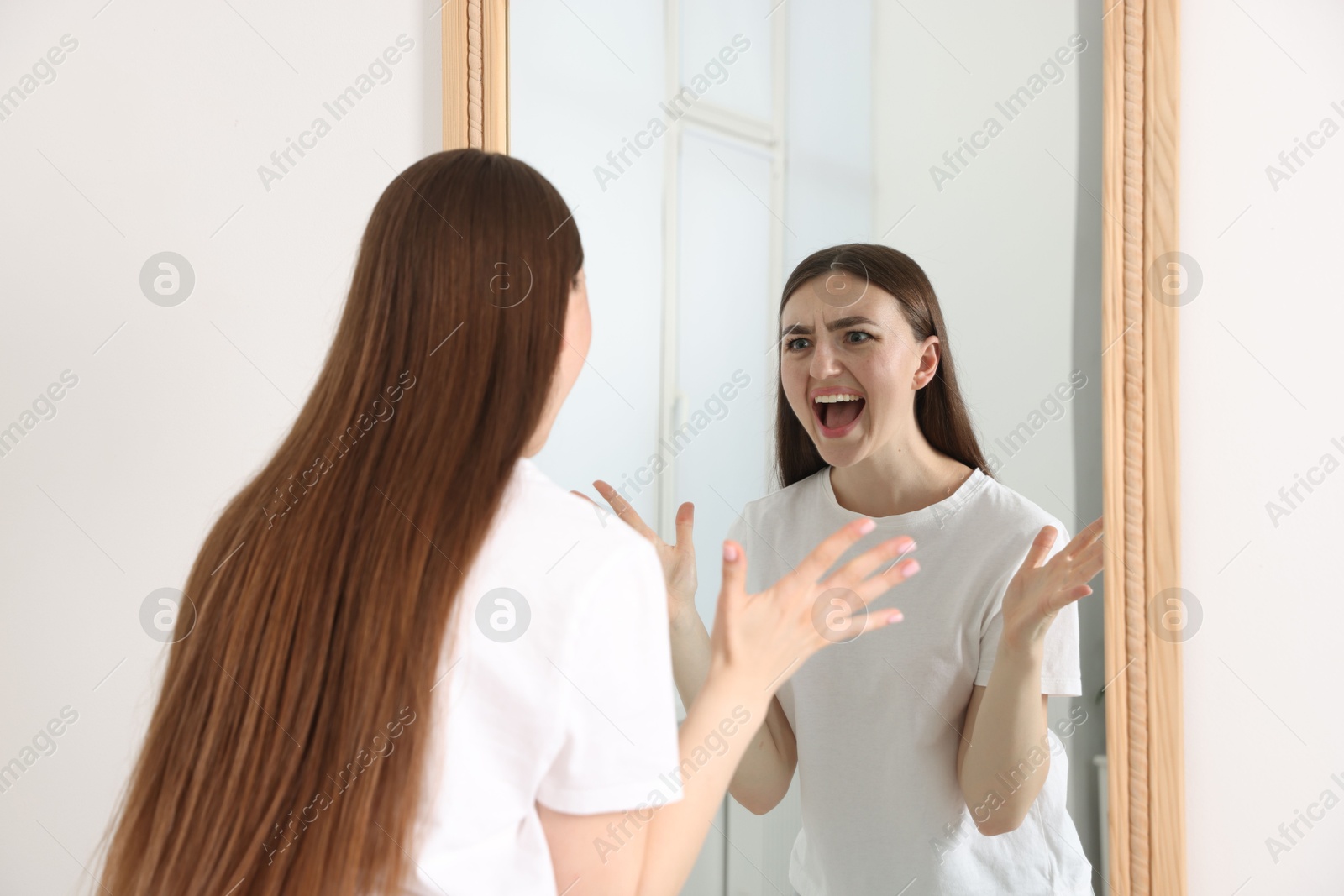 Beautiful woman looking at herself in mirror indoors Photo of Beautiful woman looking at herself in mirror indoors