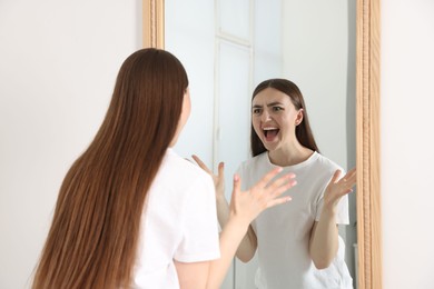 Photo of Beautiful woman looking at herself in mirror indoors