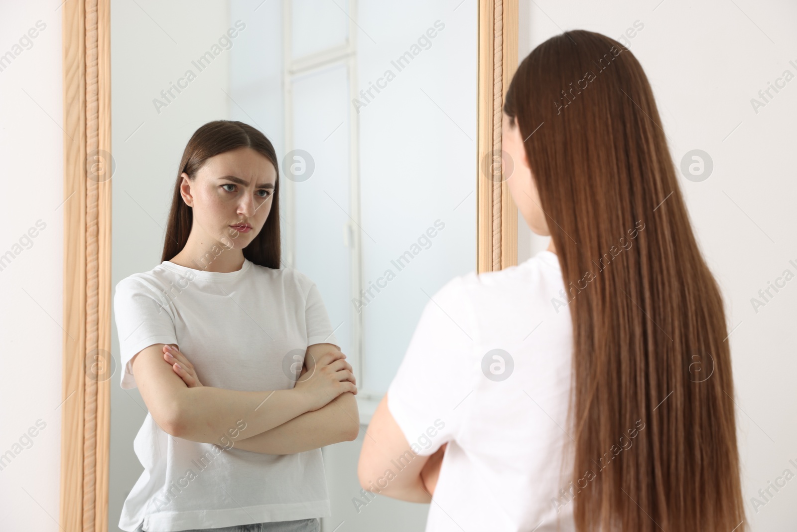 Beautiful woman looking at herself in mirror indoors Photo of Beautiful woman looking at herself in mirror indoors