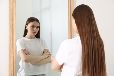 Photo of Beautiful woman looking at herself in mirror indoors
