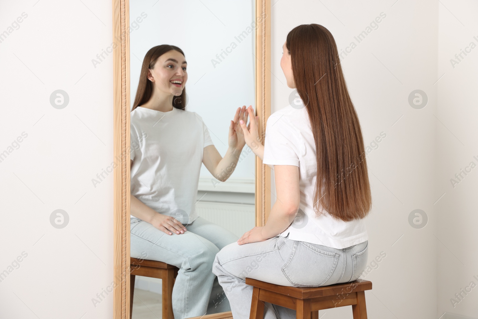 Beautiful woman looking at herself in mirror indoors Photo of Beautiful woman looking at herself in mirror indoors