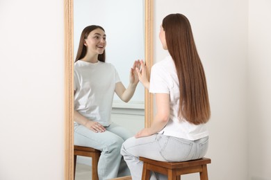 Photo of Beautiful woman looking at herself in mirror indoors