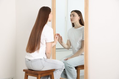 Photo of Beautiful woman looking at herself in mirror indoors