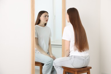 Photo of Beautiful woman looking at herself in mirror indoors