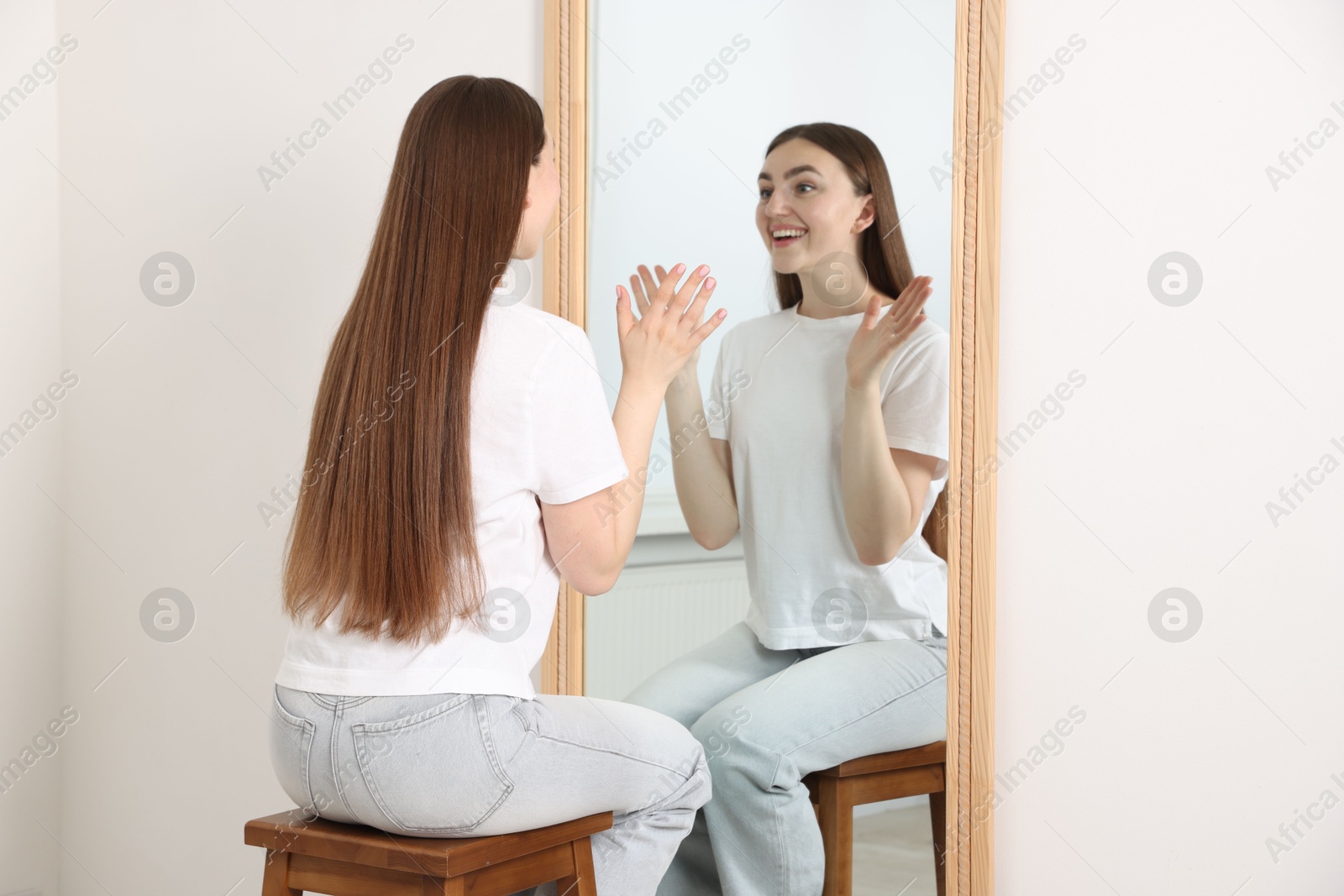 Beautiful woman looking at herself in mirror indoors Photo of Beautiful woman looking at herself in mirror indoors