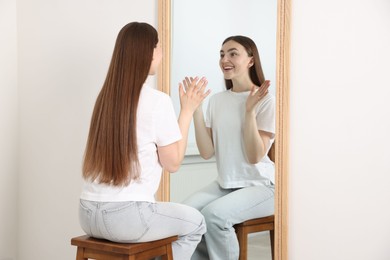 Photo of Beautiful woman looking at herself in mirror indoors