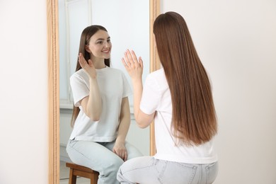 Photo of Beautiful woman looking at herself in mirror indoors