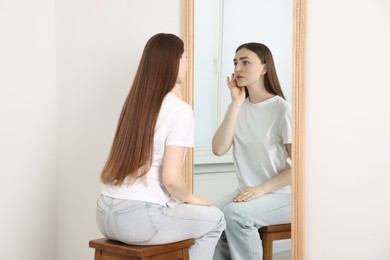 Photo of Beautiful woman looking at herself in mirror indoors