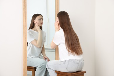 Photo of Beautiful woman looking at herself in mirror indoors