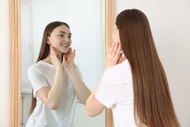 Photo of Beautiful woman looking at herself in mirror indoors