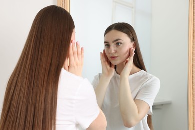 Photo of Beautiful woman looking at herself in mirror indoors