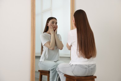 Photo of Beautiful woman looking at herself in mirror indoors