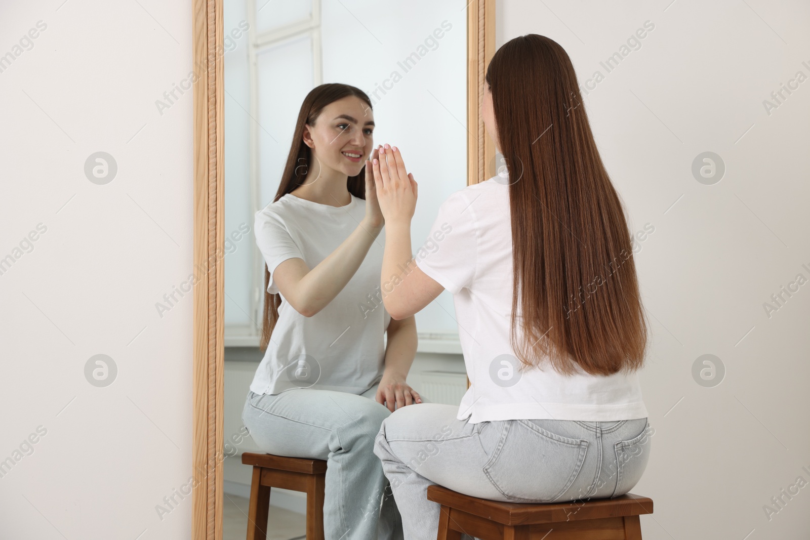 Beautiful woman looking at herself in mirror indoors Photo of Beautiful woman looking at herself in mirror indoors
