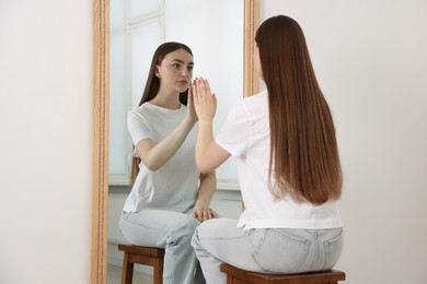 Photo of Beautiful woman looking at herself in mirror indoors