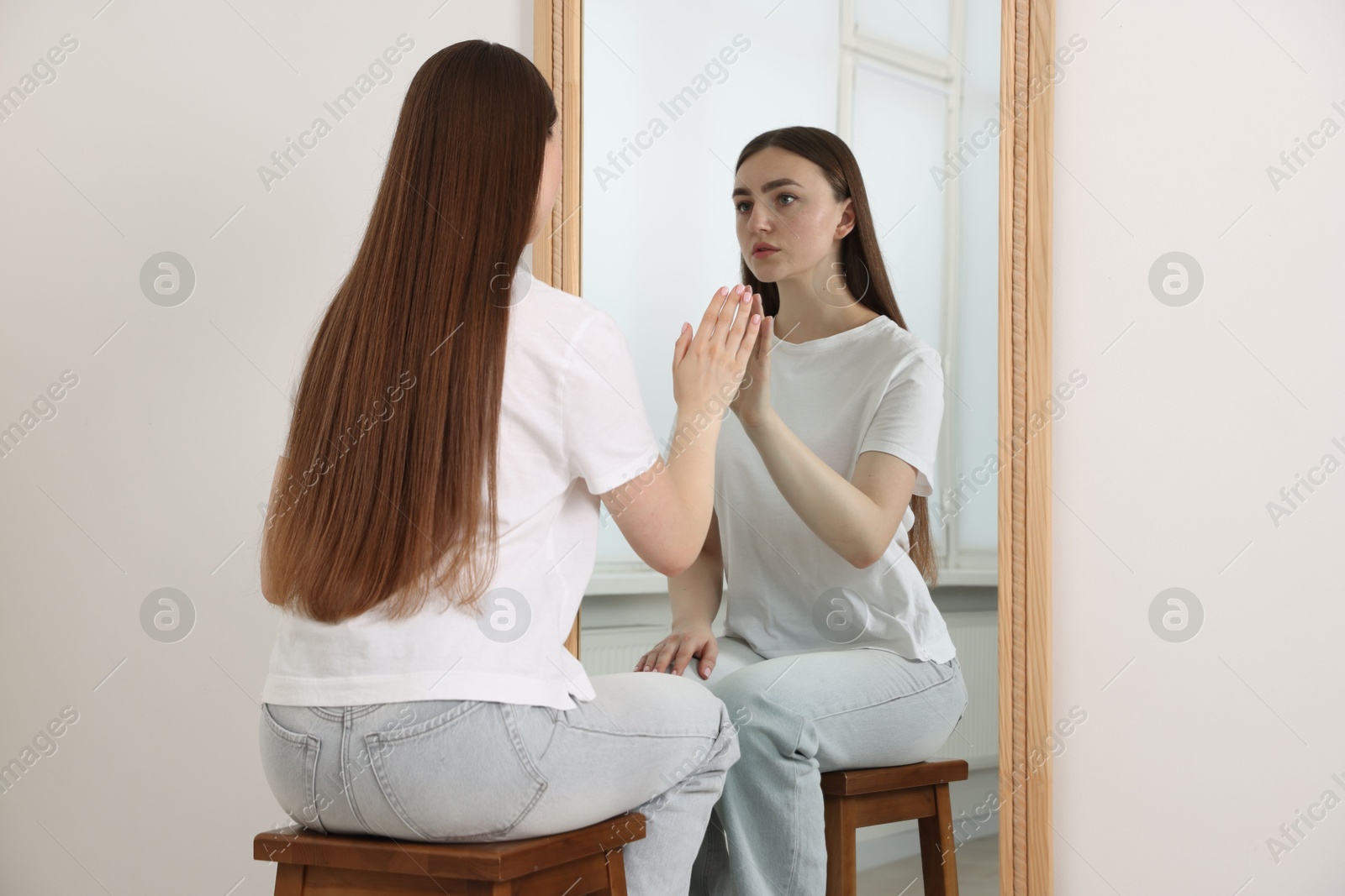 Beautiful woman looking at herself in mirror indoors Photo of Beautiful woman looking at herself in mirror indoors