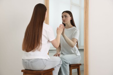 Photo of Beautiful woman looking at herself in mirror indoors