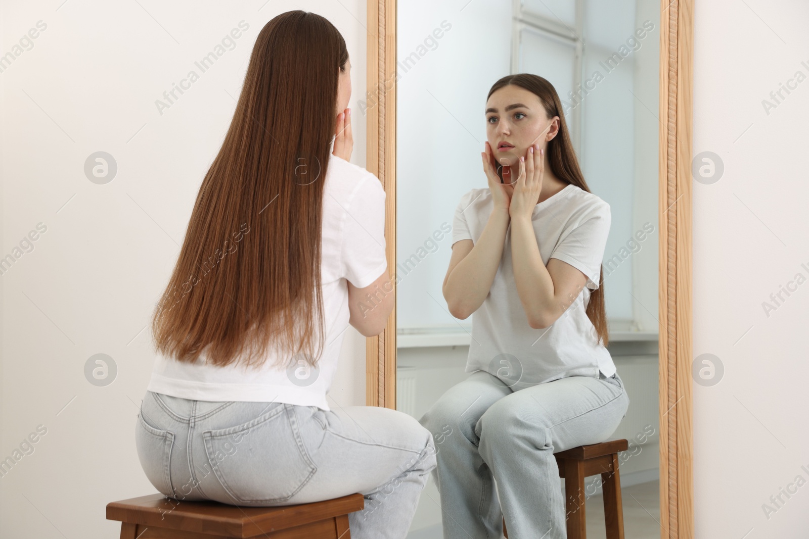 Beautiful woman looking at herself in mirror indoors Photo of Beautiful woman looking at herself in mirror indoors