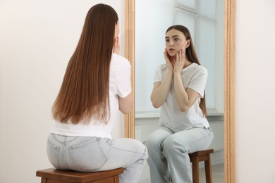 Photo of Beautiful woman looking at herself in mirror indoors