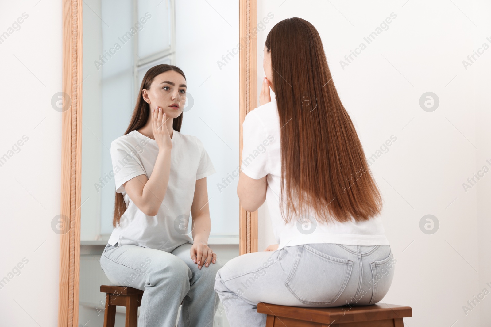 Beautiful woman looking at herself in mirror indoors Photo of Beautiful woman looking at herself in mirror indoors