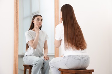 Photo of Beautiful woman looking at herself in mirror indoors